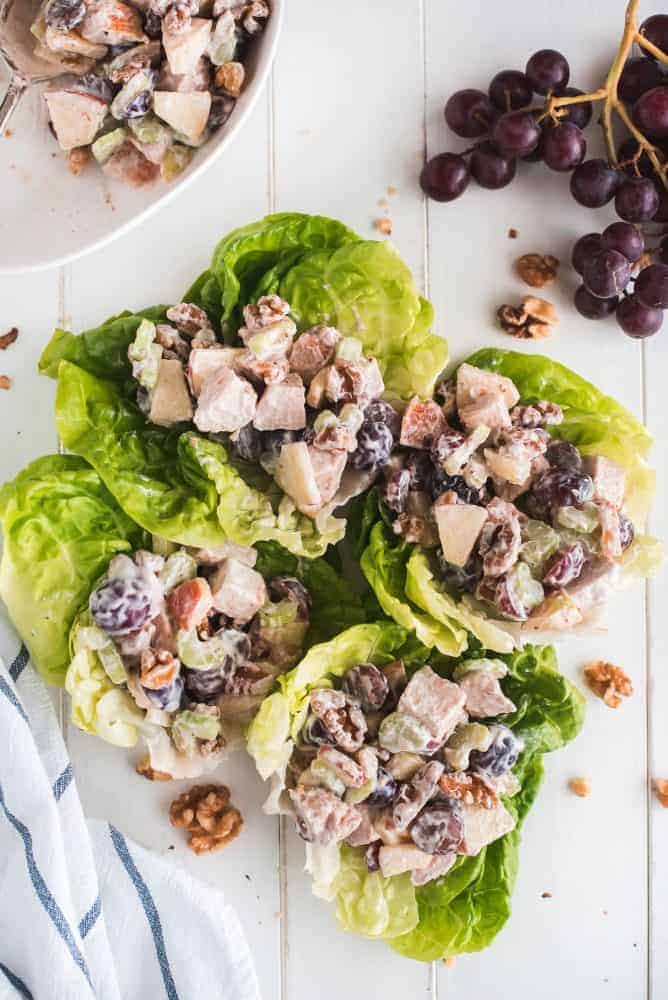 This Waldorf Chicken Salad is a refreshing and filling dish loaded with fruit, veggies, and nuts. It comes together quickly and packs up well for taking to work or even a picnic. Four lettuce leaves topped with Waldorf Chicken Salad.
