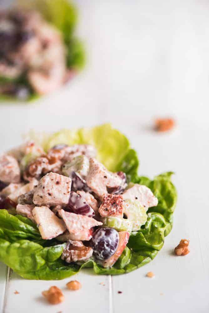 This Waldorf Chicken Salad is a refreshing and filling dish loaded with fruit, veggies, and nuts. It comes together quickly and packs up well for taking to work or even a picnic. Waldorf Chicken Salad on a leaf of lettuce.