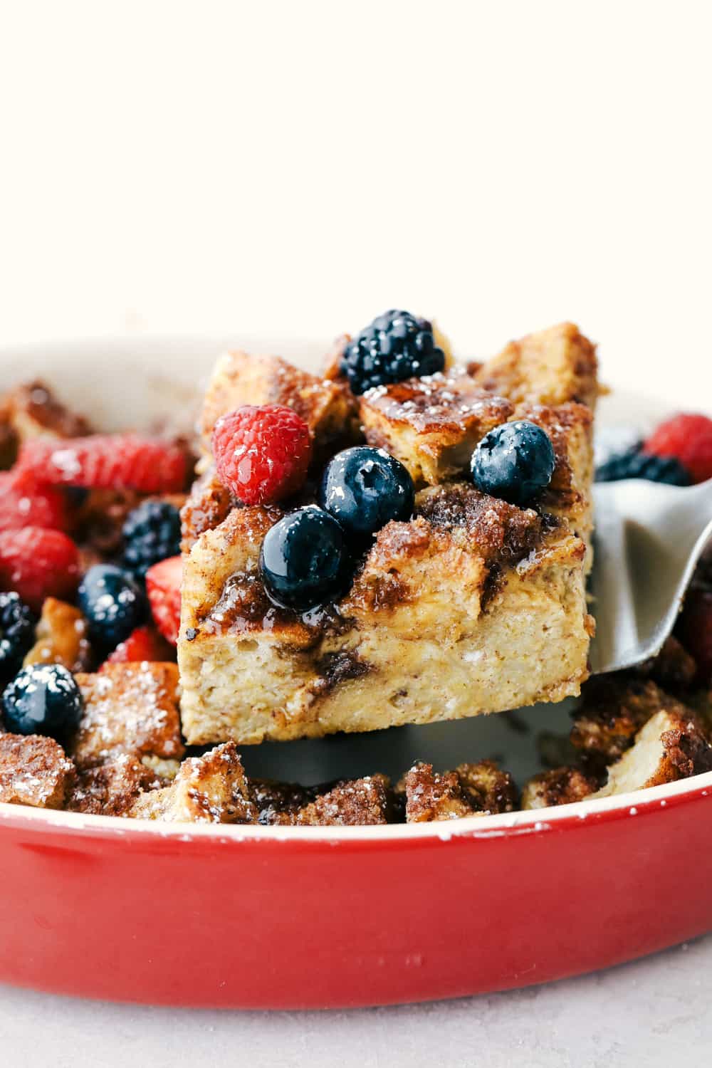 Cinnamon baked French toast is a delicious breakfast casserole full of cinnamon sugar goodness! Soft brioche bread pieces get baked in a sweet creamy custard. French toast has never been easier! Close view of a spatula lifting baked French toast out of the pan.