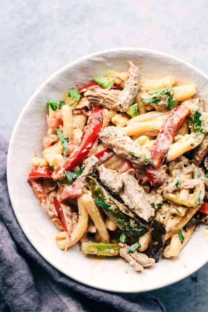 Creamy Pork Carnitas Pasta has crazy tender seasoned fresh pork with peppers and creamy pasta. All of the flavors you love about carnitas packed into a delicious meal! Creamy Pork Carnitas Pasta in a white bowl.