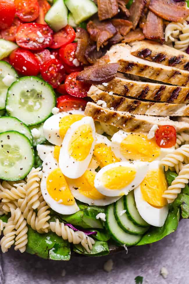 Balsamic Chicken Cobb Salad has all the classic flavors of the popular favorite with a simple balsamic dressing. Made with lettuce, tomatoes, bacon, cucumber, avocado, cheese and rotini - perfect for lunch or your next potluck! Closeup of Balsamic Chicken Cobb Salad.