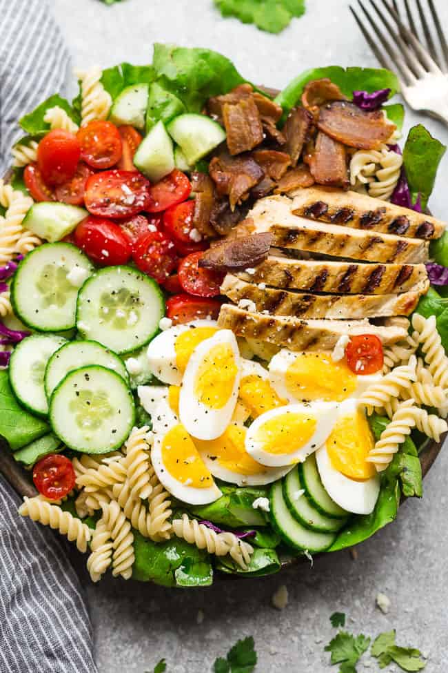 Balsamic Chicken Cobb Salad has all the classic flavors of the popular favorite with a simple balsamic dressing. Made with lettuce, tomatoes, bacon, cucumber, avocado, cheese and rotini - perfect for lunch or your next potluck! Closeup of Balsamic Chicken Cobb Salad with two forks.