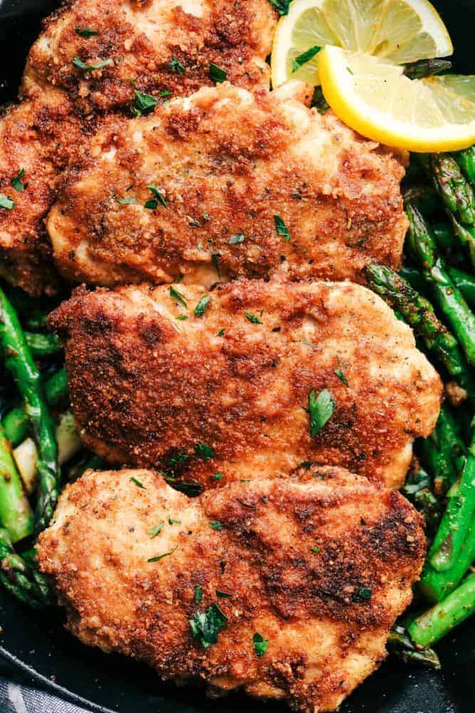 Crispy Garlic Chicken with Asparagus is an easy 30 minute meal with crispy breaded chicken and crisp and tender asparagus. This is a family favorite meal! Crispy Garlic Chicken with Asparagus with slices of lemon.