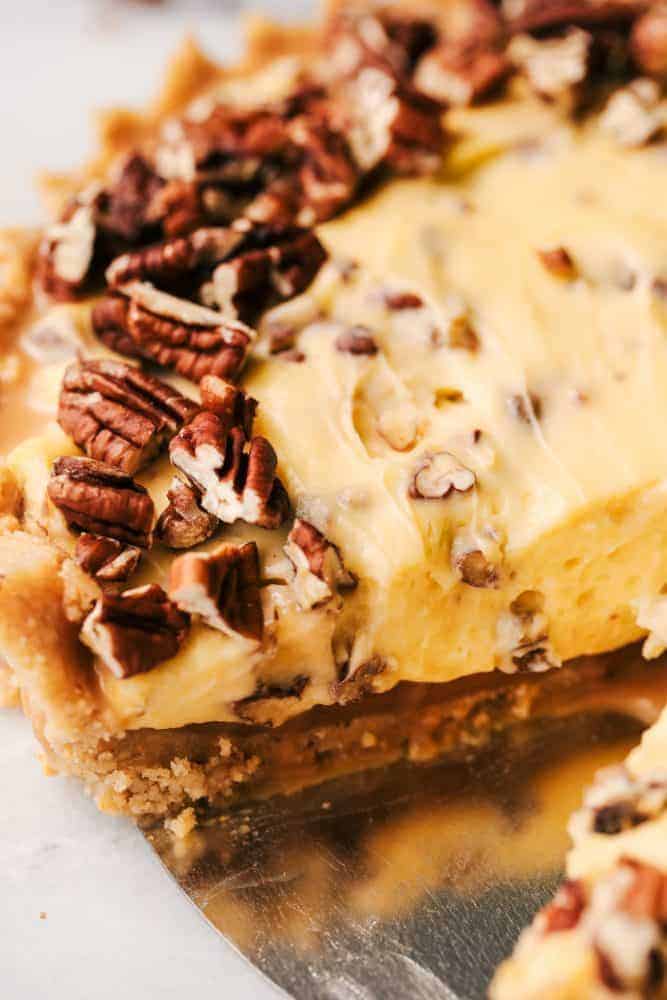 No Bake Banana Caramel Pecan Pie is made with a shortbread crust topped with caramel and a creamy banana filling with crunchy pecans. This makes one incredible no bake pie! No Bake Banana Caramel Pecan Pie with a slice removed.