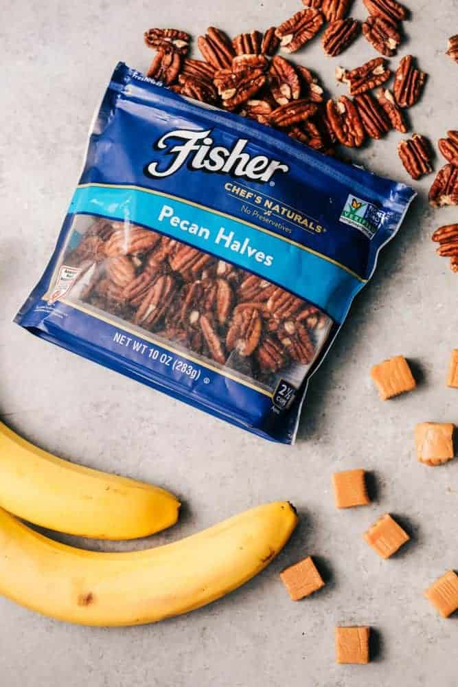 No Bake Banana Caramel Pecan Pie is made with a shortbread crust topped with caramel and a creamy banana filling with crunchy pecans. This makes one incredible no bake pie! An open bag of pecan halves with two whole bananas and caramels.