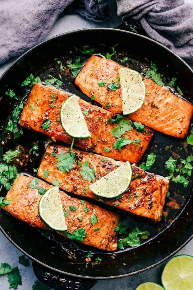 Cilantro Lime Butter Salmon is pan seared to tender and flaky perfection and has the most amazing cilantro lime butter honey sauce on top! Cilantro Lime Butter Salmon in a skillet with sliced lime on top of the salmon.
