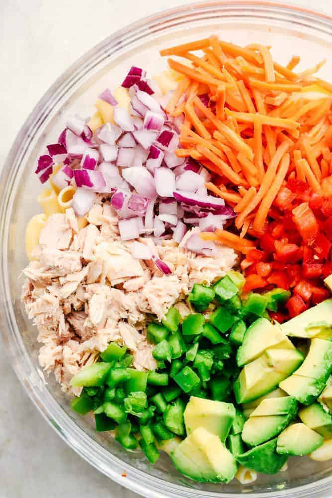 Tuna Avocado Macaroni Salad is an AMAZING creamy macaroni salad that is filled with chopped veggies, avocado, and tuna. This is going to impress everyone at your next potluck! Ingredients for Tuna Avocado Macaroni Salad in a clear bowl.