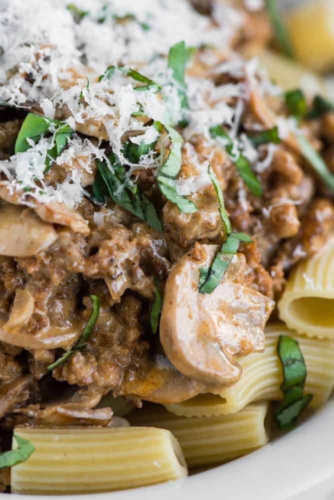 Creamy Sausage Mushroom Rigatoni is a simple Italian pasta recipe that makes for an easy and delicious dinner in less than 30 minutes! This meal isย is pure comfort food that the entire family will love. Close up of Creamy Sausage Mushroom Rigatoni in a white bowl.