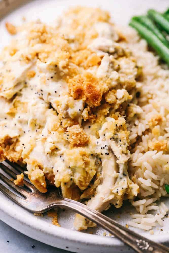 Poppyseed Chicken Casserole is such a classic dish that is incredibly easy to make! A creamy chickenย casserole topped with a buttery ritz topping. This will be the best you ever make!ย Poppyseed Chicken Casserole on a white plate with green beens on the side.