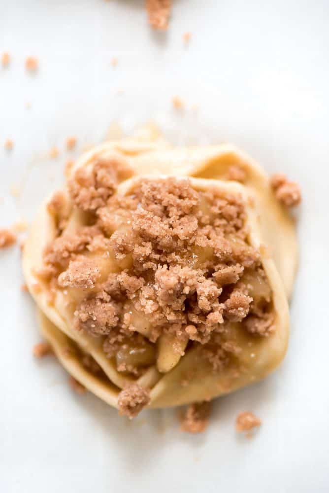 Apple Danishes are the perfect way to ring in the apple season! The flaky crust, apple pie filling, crumb topping, and simple glaze make them irresistible. Un-cooked Apple Danish with crumbs on top.