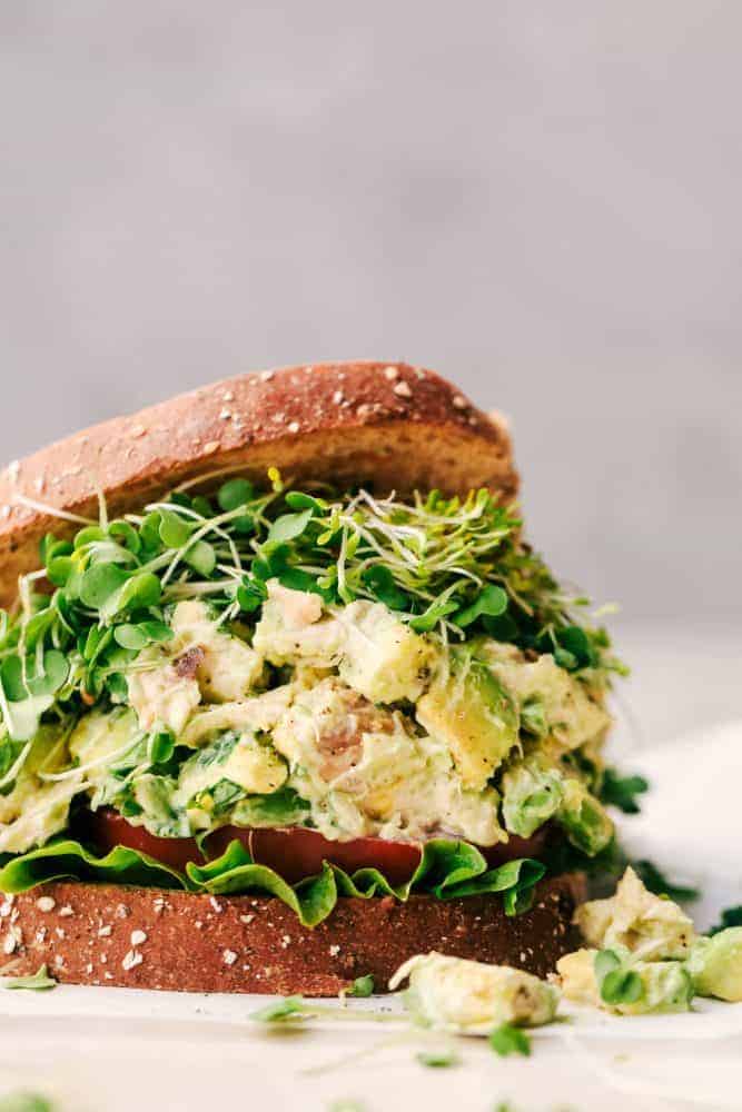 Avocado Chicken Salad is easy to make and you will never want to make your chicken salad without avocado again! Perfect on a sandwich, croissant or served with tortilla chips! Avocado Chicken Salad between two slices of bread.