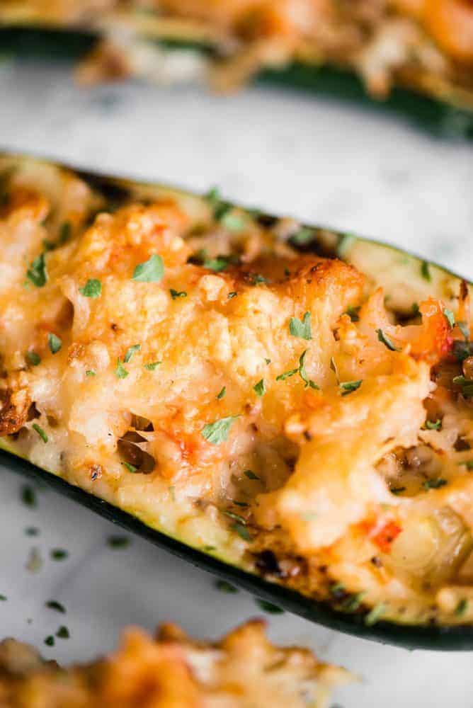 Shrimp Zucchini Boats with succulent pieces of shrimp and artichokes topped with parmesan cheese are a great low carb and tasty way to enjoy zucchini! Close up of Shrimp Zucchini Boat.