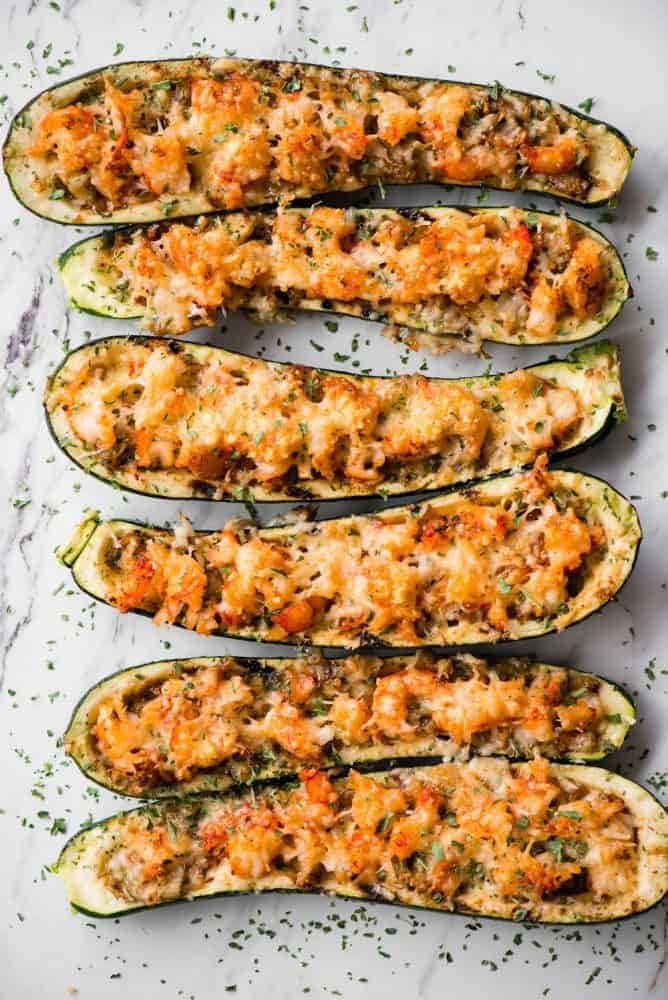 Shrimp Zucchini Boats with succulent pieces of shrimp and artichokes topped with parmesan cheese are a great low carb and tasty way to enjoy zucchini! Shrimp Zucchini Boats on a table.