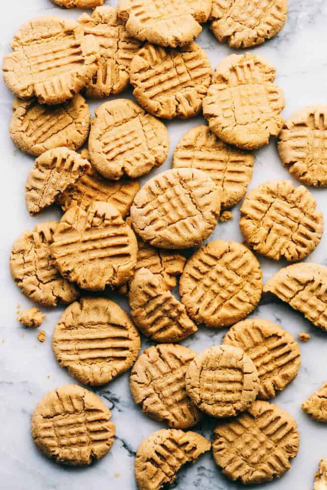Perfectly Soft Peanut Butter Cookies are such a classic recipe! This recipe makes the most perfect and soft peanut butter cookies. This will be the only recipe you ever need! Several peanut butter cookies spread out on a white granite countertop.