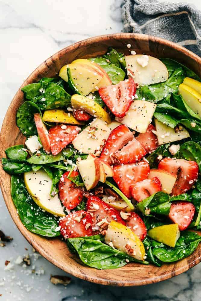 Strawberry, Apple, and Pear Spinach Salad is an easy to make spinach salad with crisp apples, pears and strawberries hidden throughout. Topped with feta cheese, crunchy pecans and tossed in a delicious apple cider dressing! Strawberry, Apple, and Pear Spinach Salad in a wood bowl.