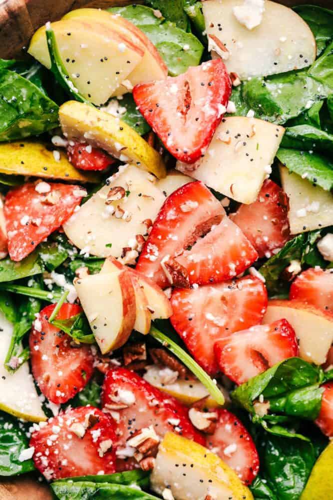 Strawberry, Apple, and Pear Spinach Salad is an easy to make spinach salad with crisp apples, pears and strawberries hidden throughout. Topped with feta cheese, crunchy pecans and tossed in a delicious apple cider dressing! Close up of Strawberry, Apple, and Pear Spinach Salad.