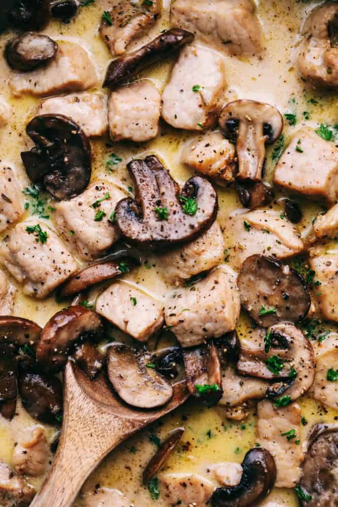 Creamy Garlic Pork Marsalaย is a 30 minute dish that has the most amazing creamy garlic marsala sauce with tender, juicy, fresh pork and mushrooms hidden inside.ย This meal is a unique spin on a traditional chicken marsala dish, and will be on repeat becauseย itsย perfect for busy nights!ย Close up of Creamy Garlic Pork Marsala with a wooden spoon.