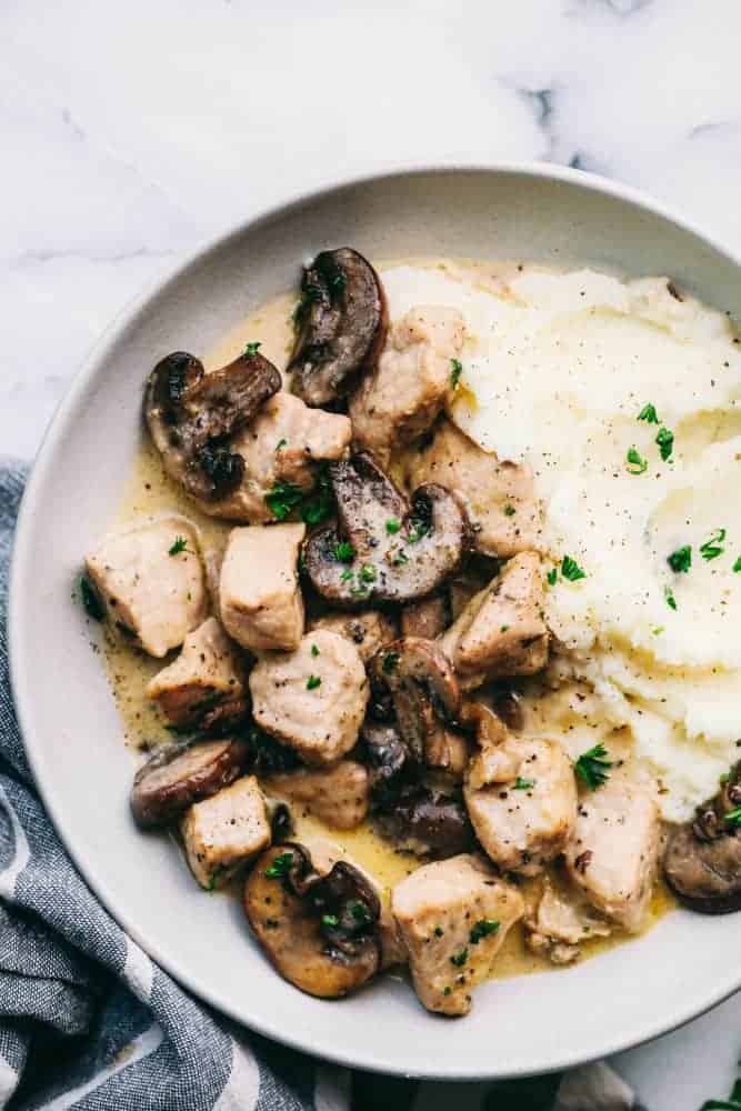 Creamy Garlic Pork Marsalaย is a 30 minute dish that has the most amazing creamy garlic marsala sauce with tender, juicy, fresh pork and mushrooms hidden inside.ย This meal is a unique spin on a traditional chicken marsala dish, and will be on repeat becauseย itsย perfect for busy nights!ย Plate of Creamy Garlic Pork Marsala with mashed potatoes.