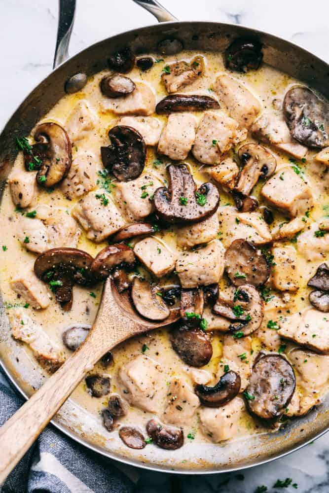 Creamy Garlic Pork Marsalaย is a 30 minute dish that has the most amazing creamy garlic marsala sauce with tender, juicy, fresh pork and mushrooms hidden inside.ย This meal is a unique spin on a traditional chicken marsala dish, and will be on repeat becauseย itsย perfect for busy nights!ย Creamy Garlic Pork Marsala in a frying pan with a wooden spoon.