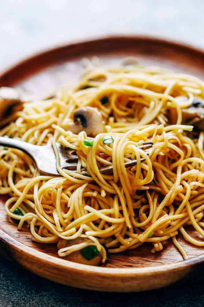 Garlic Mushroom Noodles is an easy side that goes well with grilled chicken, pork chops or asian mains. Silky smooth egg noodles are tossed in a quick sauce with sauteed mushrooms and lots of golden garlic! Garlic Mushroom Noodles served on a brown plate.