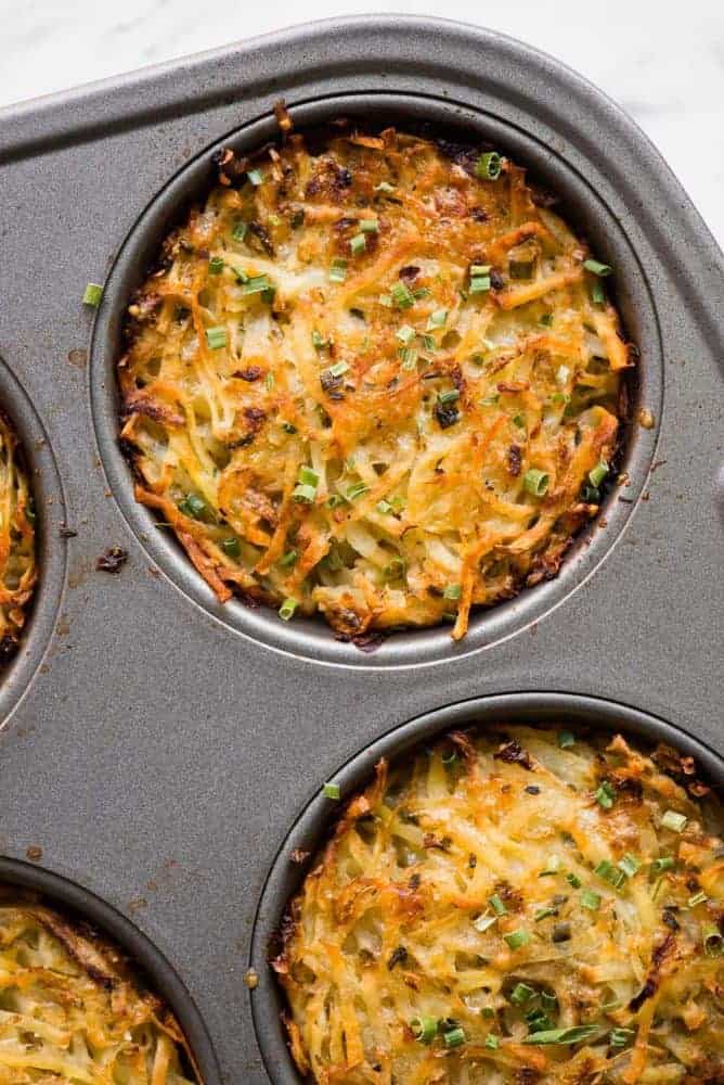 Baked Parmesan Hashbrowns, baked to golden brown perfection and made with freshly grated potatoes, are a breakfast favorite! They are loaded with flavor and are the perfect addition to your hearty breakfast. If you love traditional hashbrowns, then you will really love these Baked Parmesan Hashbrowns! Baked Parmesan Hashbrowns in a muffin baking pan.
