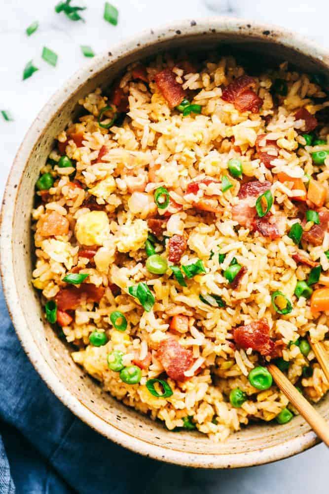 Bacon Fried Rice is 1000x better than takeout and has crispy bacon, eggs, peas, carrots and rice that combine to make the best fried rice ever! Bacon Fried Rice in a serving bowl with chop sticks.