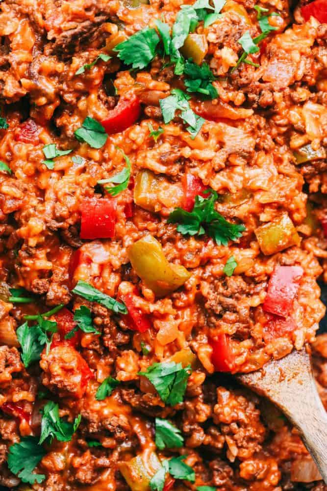 Unstuffed Pepper Skillet has all of the things that you loved about a stuffed pepper in an easy to make skillet meal! This is loaded with ground beef, peppers, tomato sauce, and cheese, and is sure to become a new family favorite! Unstuffed Pepper Skillet with a wooden spoon.