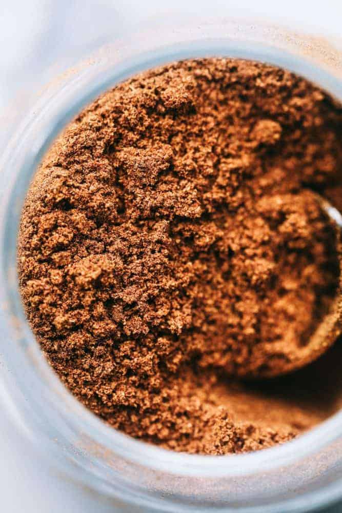 Homemade pumpkin pie spice is a fall spice staple! It's made with cinnamon, ginger, allspice, and nutmeg, which makes it perfect for cakes, pies, and cookies all season long! Close up of homemade pumpkin pie spice in a clear glass jar.