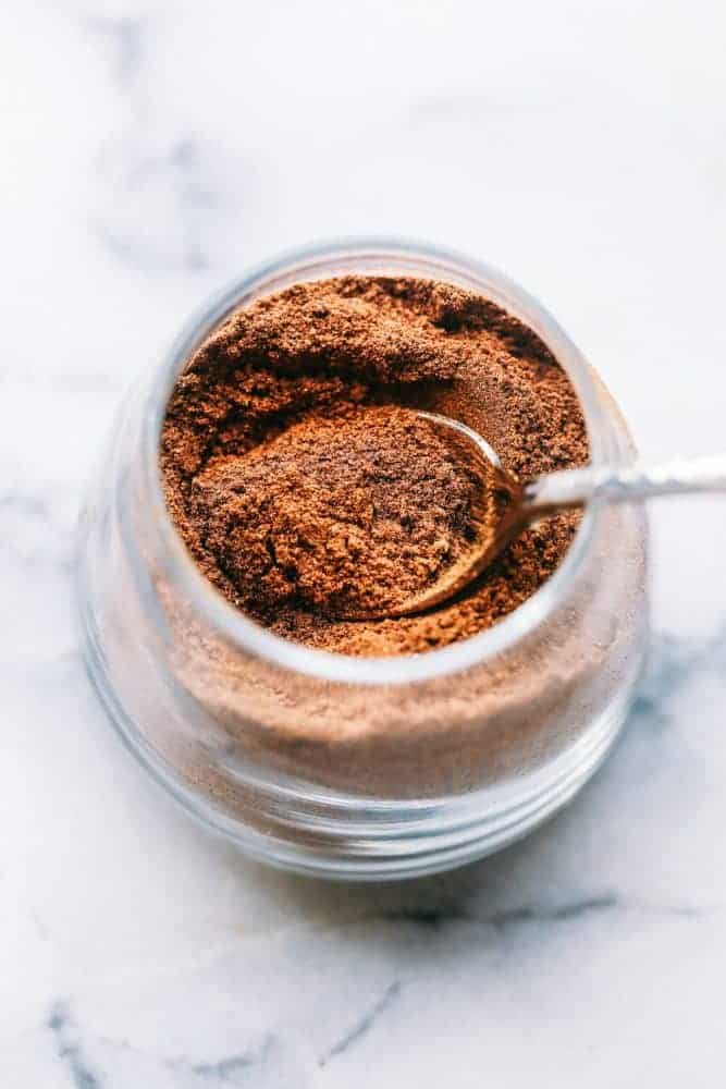 Homemade pumpkin pie spice is a fall spice staple! It's made with cinnamon, ginger, allspice, and nutmeg, which makes it perfect for cakes, pies, and cookies all season long! Spices in a clear glass jar with a metal spoon.