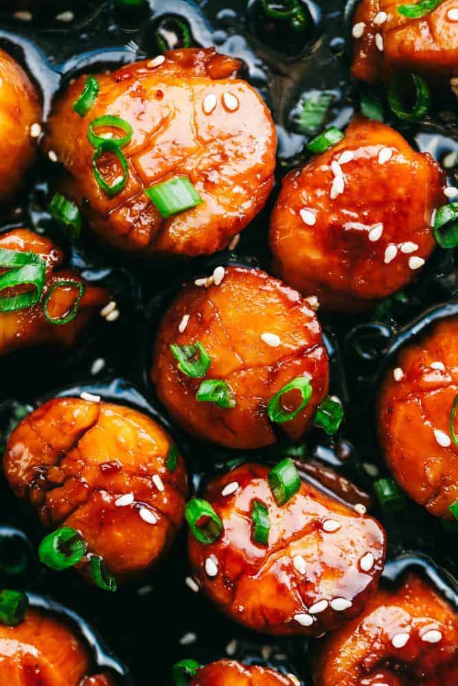 Honey Garlic Butter Scallops get pan seared and then coated in the most amazing honey garlic butter sauce. This meal is so quick and easy that you will make it again and again!ย Close up of Honey Garlic Butter Scallops.