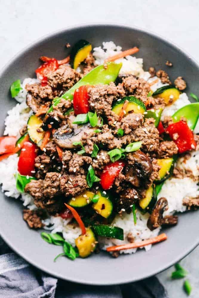 Korean Ground Beef Stir Fry is incredibly easy to make and has the best flavor! This is a recipe that my kids beg me to make every single week!ย Korean ground beef stir fry over top white rice in a gray bowl.