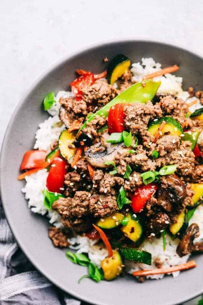 Korean Ground Beef Stir Fry is incredibly easy to make and has the best flavor! This is a recipe that my kids beg me to make every single week!ย Korean ground beef over white rice in a gray bowl sitting on a countertop.