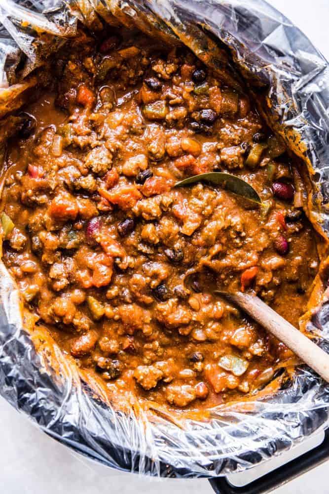 Slow Cooker Pumpkin Chili is the perfect comforting fall soup. It is hearty and packed with spices and big bold flavors. You are going to love this savory and delicious chili!ย Slow cooker pumpkin chili with a wooden ladle.