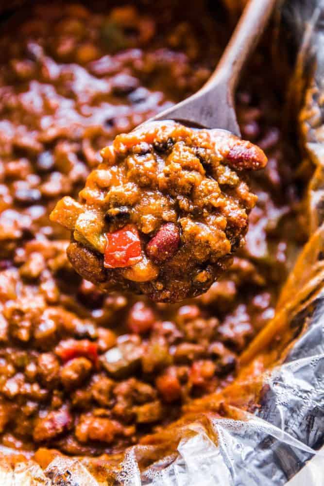 Slow Cooker Pumpkin Chili is the perfect comforting fall soup. It is hearty and packed with spices and big bold flavors. You are going to love this savory and delicious chili!ย Slow cooker pumpkin chili with a wooden spoon.