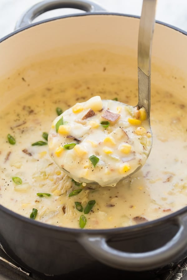 This Corn Chowder recipe is thick, hearty and perfect for a chilly fall day! It's so easy to make and perfect for your weekend meal prep! Large pot of corn chowder with a ladle removing some.
