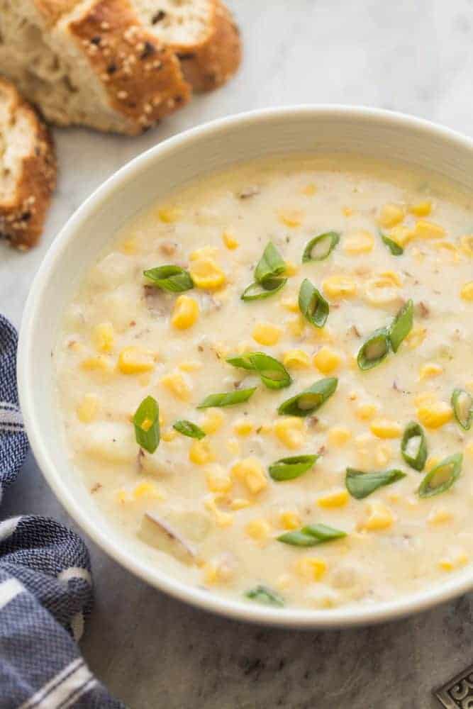 This Corn Chowder recipe is thick, hearty and perfect for a chilly fall day! It's so easy to make and perfect for your weekend meal prep. Large bowl of corn chowder with bread on the side.
