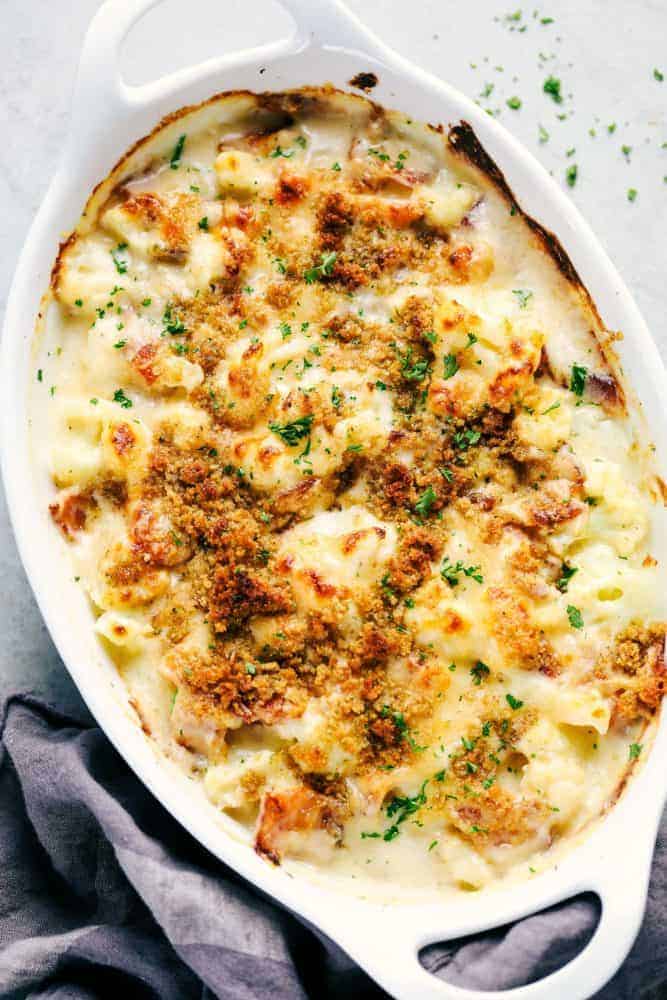 Creamy Cauliflower Au Gratin with Bacon makes such an amazing side dish. It is filled with tender cauliflower and bacon in a cheesy sauce that is topped with bread crumbs. This will be the hit of the dinner table! Creamy cauliflower gratin with bacon baked in a white casserole dish garnished with parsley.