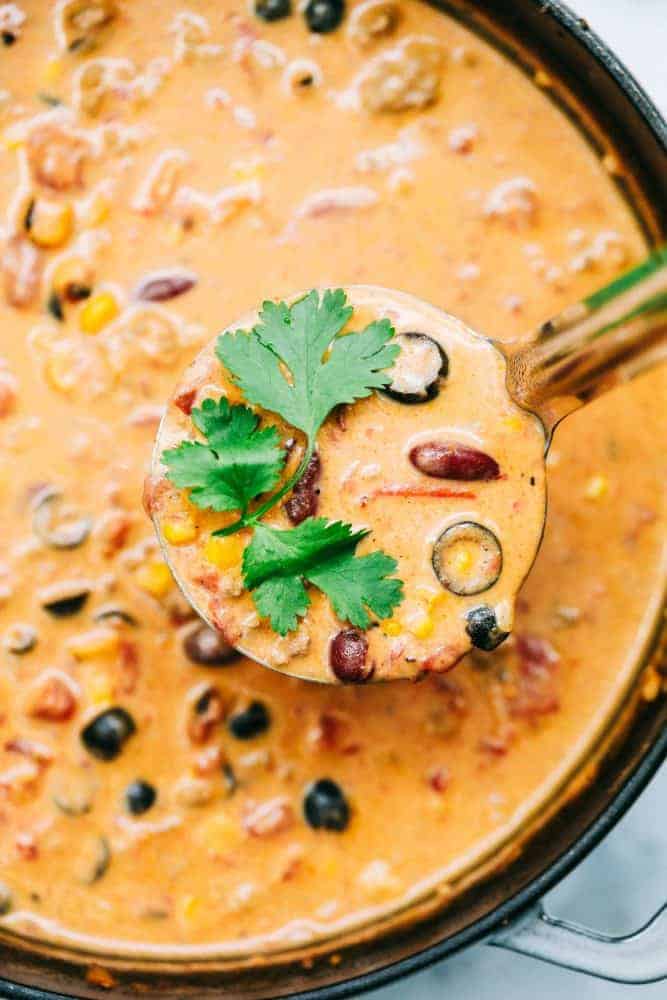 Cheesy Taco Soup is so simple to throw together and is loaded with taco inspired ingredients. The cheesiness takes this soup to the next level of delicious and will be loved by the entire family! Large bowl and ladle with Cheesy Taco Soup.