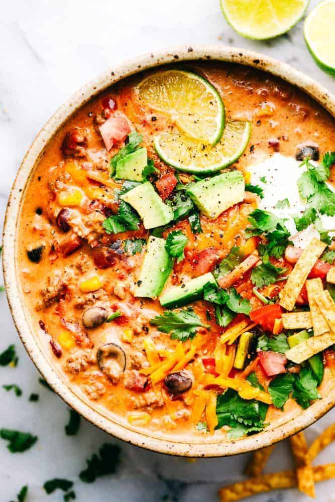 Cheesy Taco Soup is so simple to throw together and is loaded with taco inspired ingredients. The cheesiness takes this soup to the next level of delicious and will be loved by the entire family! A bowl of Cheesy Taco Soup with fresh sliced limes on top.