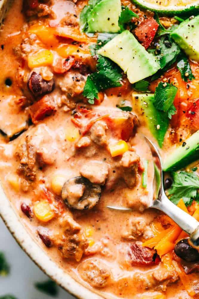 Cheesy Taco Soup is so simple to throw together and is loaded with taco inspired ingredients. The cheesiness takes this soup to the next level of delicious and will be loved by the entire family! Cheesy Taco Soup in a bowl with a metal spoon.