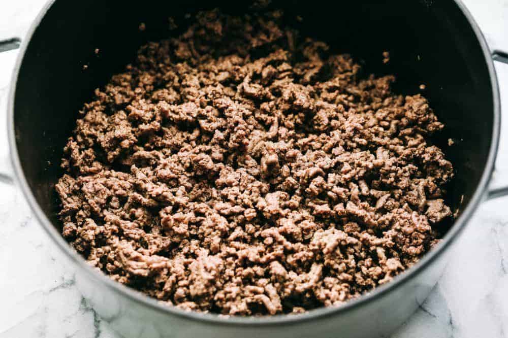 Cheesy Taco Soup is so simple to throw together and is loaded with taco inspired ingredients. The cheesiness takes this soup to the next level of delicious and will be loved by the entire family! Cooked ground beef in a large pot.
