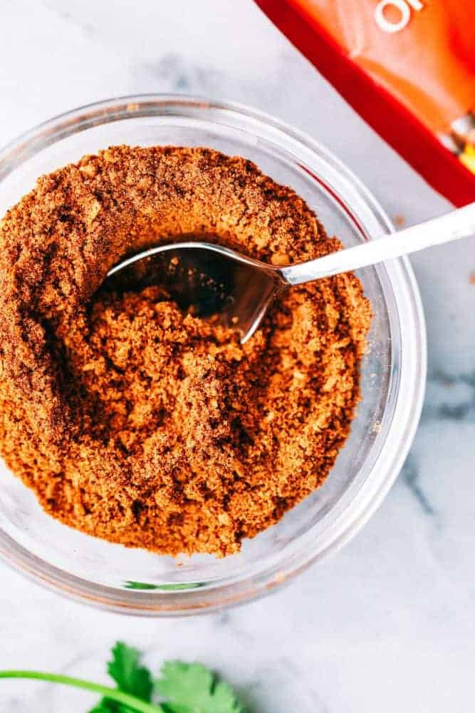 Cheesy Taco Soup is so simple to throw together and is loaded with taco inspired ingredients. The cheesiness takes this soup to the next level of delicious and will be loved by the entire family! Taco seasoning in a clear glass bowl.