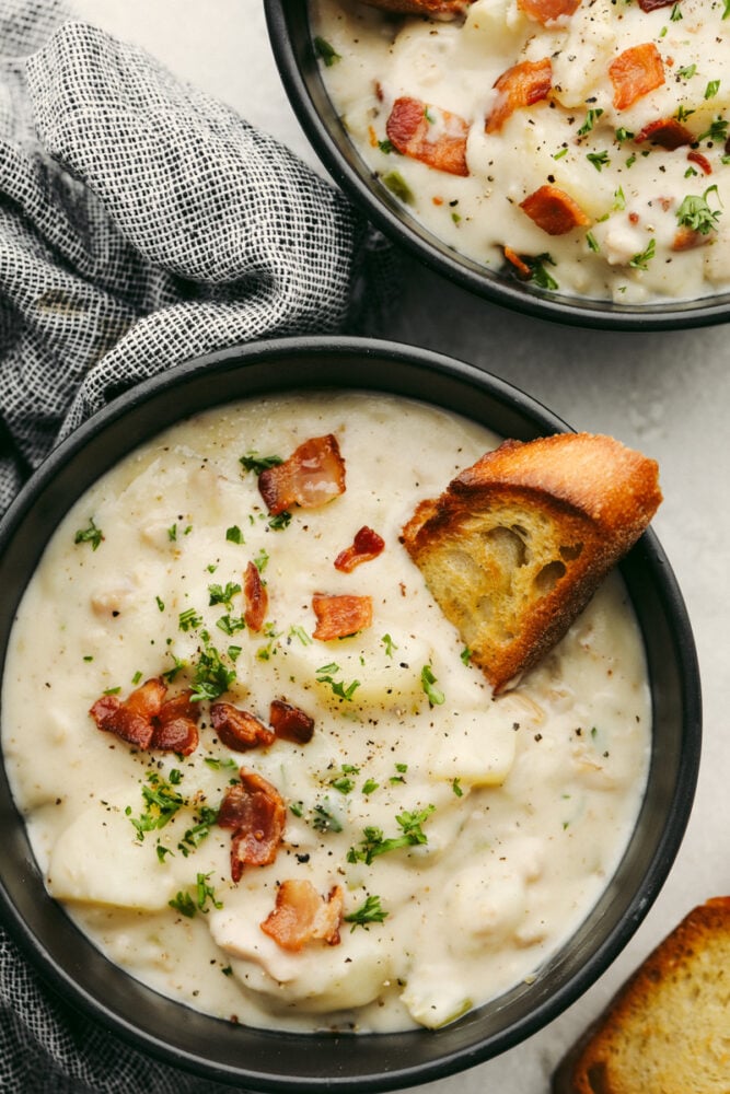 Creamy Clam Chowder with potatoes and vegetables is one of my favorite easy soup recipes! It's thick and creamy and tastes as if it came straight from a restaurant! It's SOO GOOD! A bowl of clam chowder with a crostini in it.