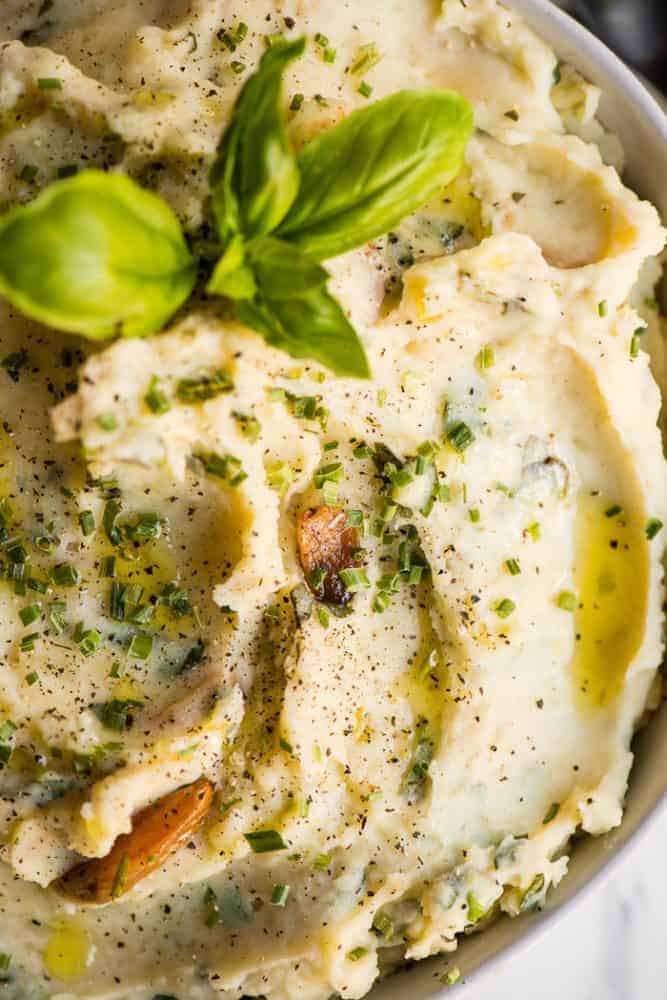 Garlic Herb Mashed Potatoes, made with roasted garlic, fresh herbs, and gold potatoes, are an easy side dish recipe perfect for dinner! A close up photo of garlic herb mashed potatoes.