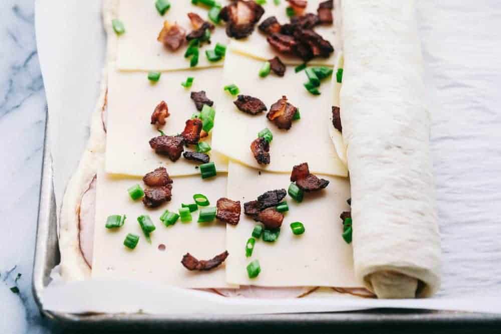 Easy Ham and Swiss Stromboliย can be anything you want it to be! Breakfast? Yes. Brunch? You bet. Dinner? Of course! This meal is a triple threat. It's easy enough to be a side dish. But so good it will be the star of the table.ย Ham and Swiss Stromboli being rolled up.