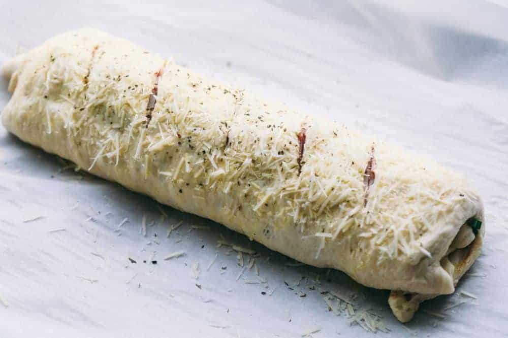 Easy Ham and Swiss Stromboliย can be anything you want it to be! Breakfast? Yes. Brunch? You bet. Dinner? Of course! This meal is a triple threat. It's easy enough to be a side dish. But so good it will be the star of the table.ย Uncooked Ham and Swiss Stromboli rolled up and ready for the oven.