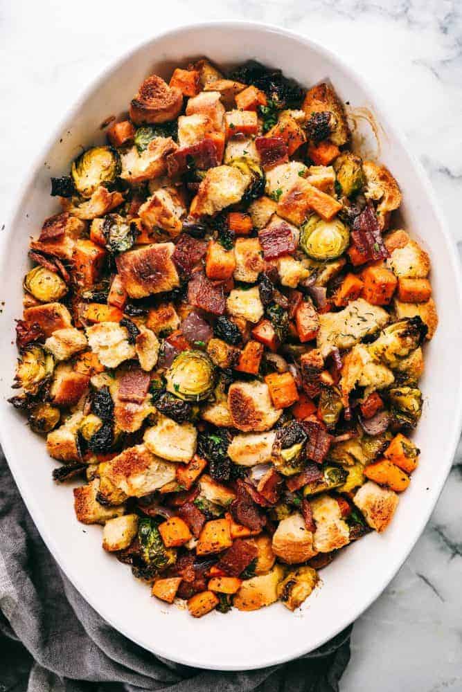 Roasted Autumn Vegetable Stuffing is the perfect side dish for your holiday meal. Filled with roasted autumn vegetables and bacon, this is the perfect addition to the dinner table. .Roasted Autumn Vegetable Stuffing in a white dish.