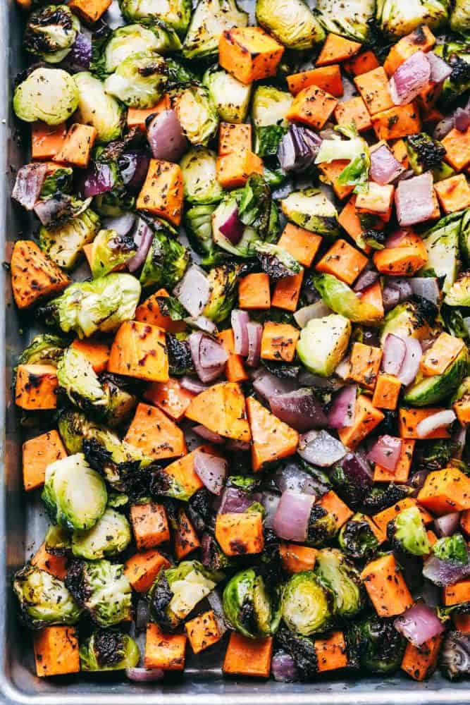 Roasted Autumn Vegetable Stuffing is the perfect side dish for your holiday meal. Filled with roasted autumn vegetables and bacon, this is the perfect addition to the dinner table. A baking sheet full of chopped up carrots, red onions and brussels sprouts with McCormick seasoning.