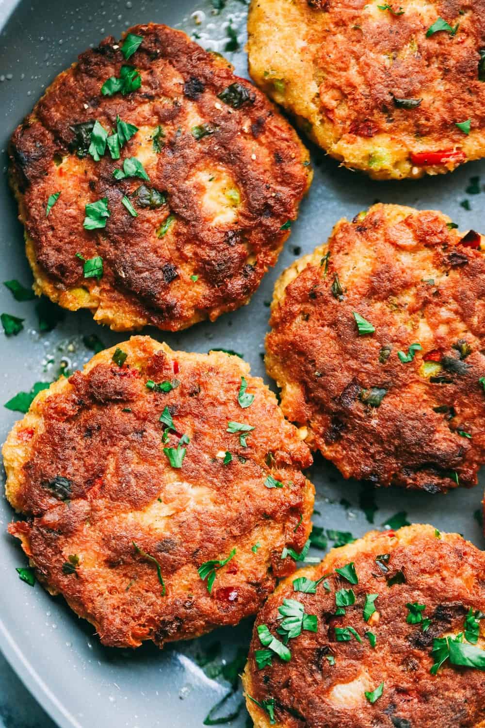 Salmon Croquettes are pan fried and packed with so many great flavors. These make a quick and easy weeknight meal and areย delicious with aย tartarย sauce!ย Close up of Salmon Croquettes in a frying pan.