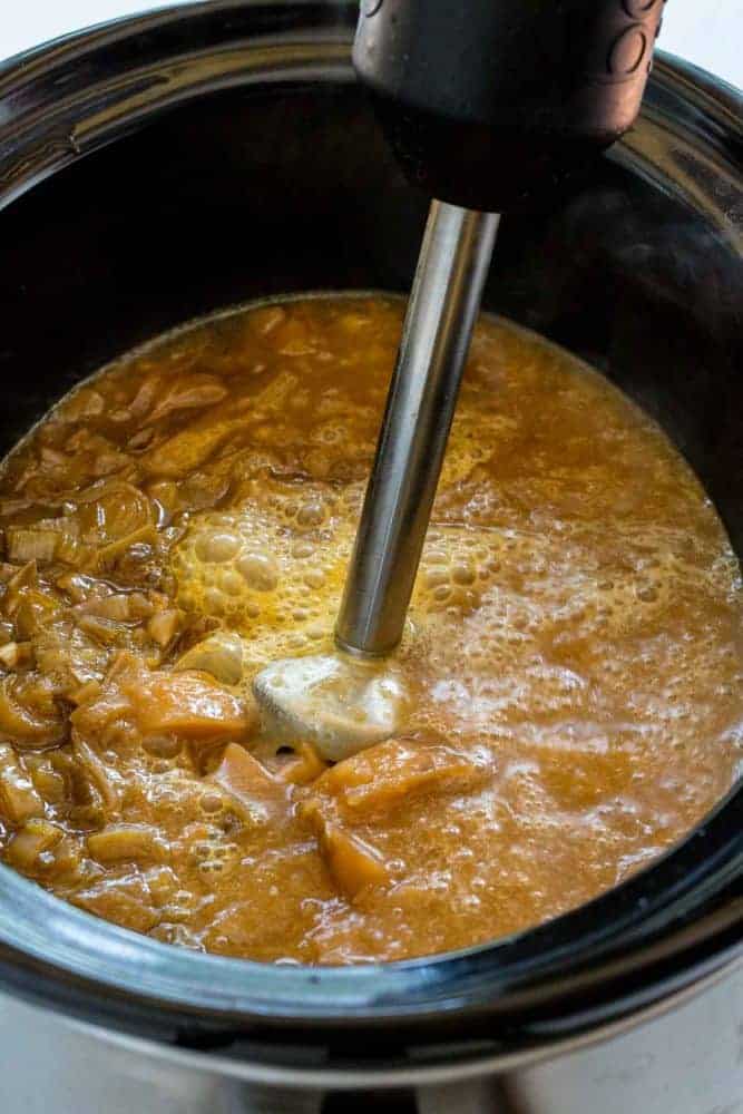 Slow Cooker Potato Leek Soup serves up a satisfying bowl of creamy pureed vegetables. The caramelized onions and leeks bump up the flavor as it gently simmers with the flaky potatoes and herbs. You wonโt believe how easy it is to create a restaurant quality dish in the crock-pot! Immersion blender being used to mix the potato leek soup inside a Crock Pot